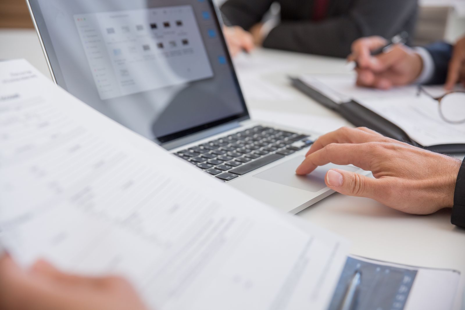 Profissionais analisando documentos empresariais ao lado de um notebook