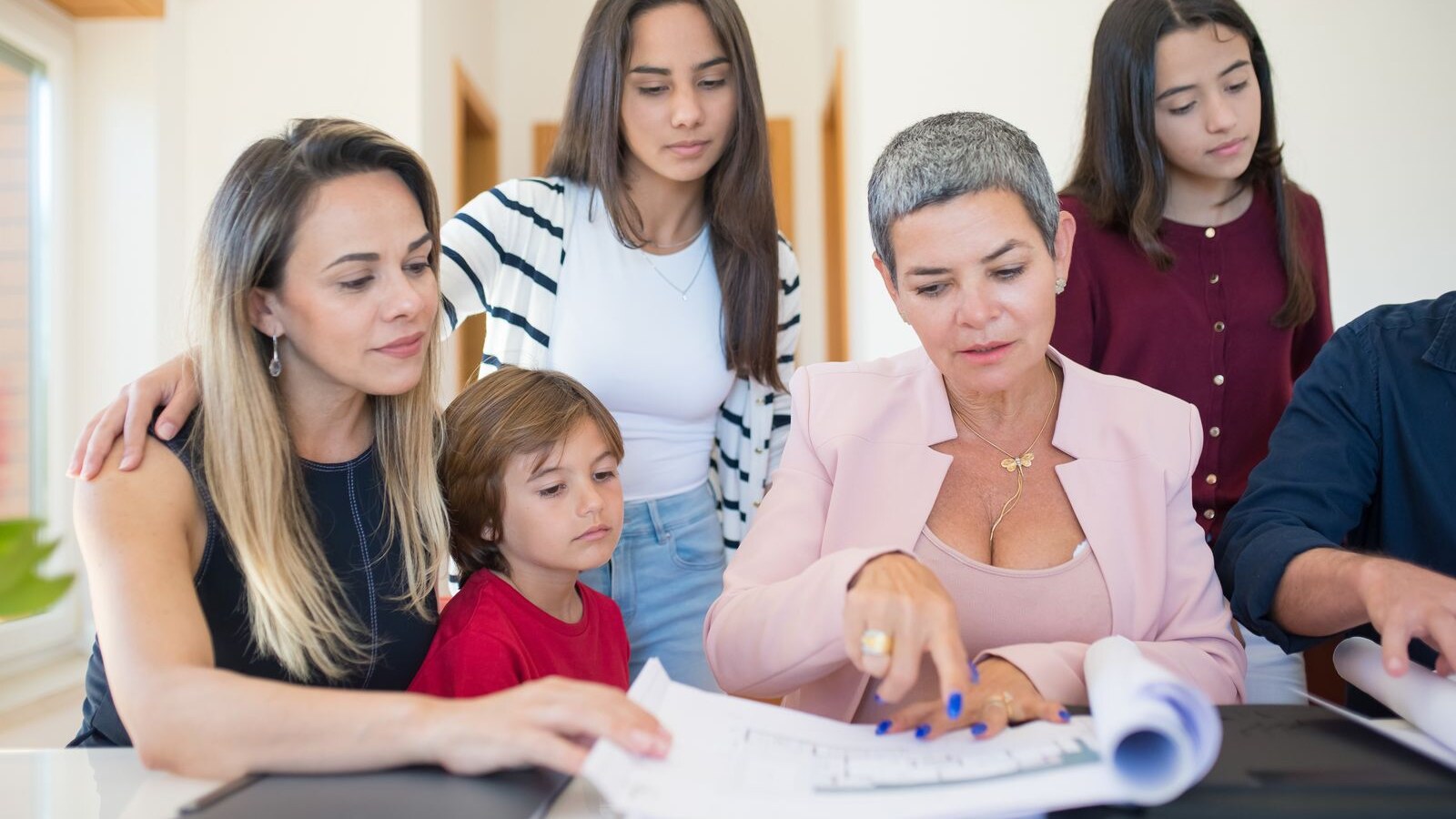 Família reunida à mesa analisando documentos com uma profissional